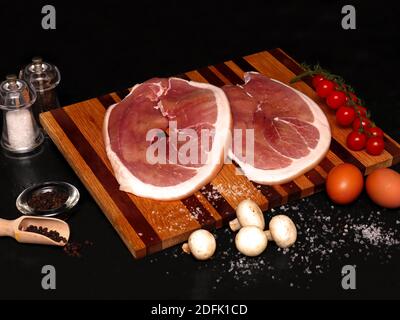 Zwei große Gammon Steaks liegen auf einem Holzbrett frisch Von den Metzgern Stockfoto