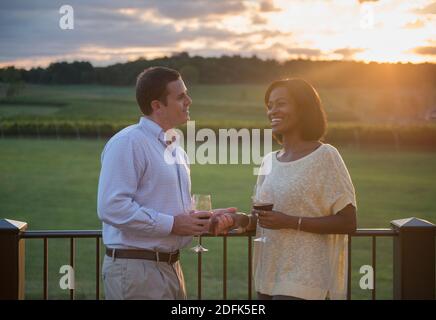 Ein junges Paar genießt im Sommer ein Glas Wein auf einem Balkon. Stockfoto