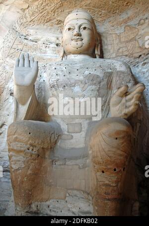 Yungang Grotten in der Nähe von Datong in der Provinz Shanxi, China. Große alte Statue von Buddha in einer Höhle bei Yungang. Hochformat von vorne. Stockfoto