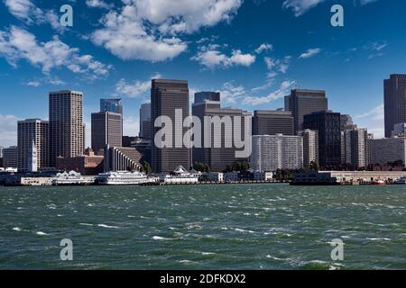 Blick auf windgeblasenes Wasser und Türme in der Innenstadt mit teilweise bewölktem Himmel in der Bucht von San Francisco. Stockfoto