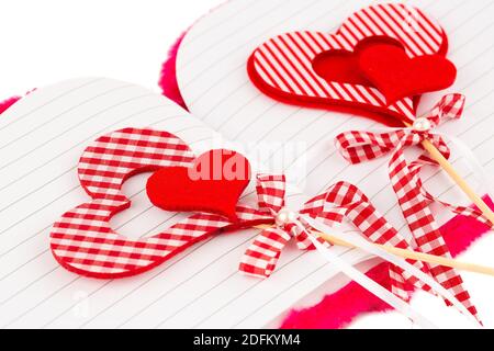 Rote Herzen mit geöffnetem Notizblock auf weißem Hintergrund. Stockfoto