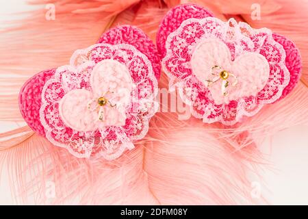 Zwei rosa Herzen mit Spitze auf Federn Hintergrund. Stockfoto