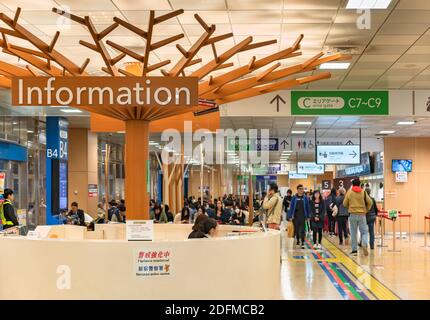 tokio, japan - november 05 2019: Menschenmenge im Warteraum des Shinjuku Bus Terminal Büros mit einem Informationstheke in Form eines Baumes, wo Cu Stockfoto