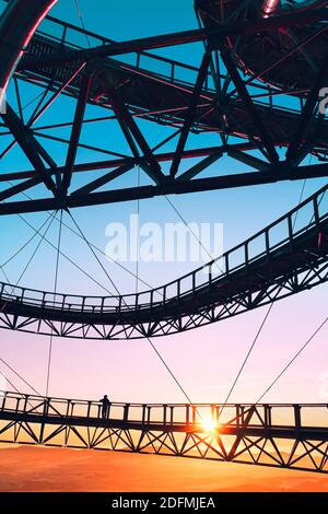 Silhouette des Mannes auf Brücke von umfangreichen Eisen-Konstruktion stehen Aussichtsturm Stezka V oblacích in Tschechien mit Aussicht Auf Hügeln bei bunter Sonne Stockfoto