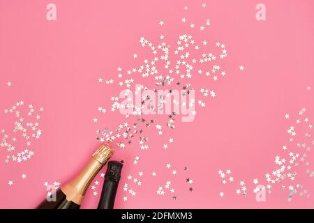 Champagner-Flasche mit Konfetti-Sternen auf rosa Hintergrund. Flat Lay of christmas, Jubiläum, Bachelorette, Neujahr Feier Konzept. Platz kopieren, t Stockfoto
