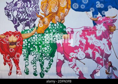 Eine indonesische Touristin verschwindet fast in einem bunten Wandbild von Büffeln in der Nähe von Buffalo Road, Little India, Singapur Stockfoto