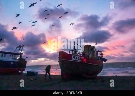 Hastings, East Sussex. Dezember 2020. Möwen wirbeln im Morgengrauen über Hastings Fischerbooten mit einem bunten Sonnenaufgang über dem Ärmelkanal, am Tag der Gespräche von Boris Johnson mit EU-Kommissionspräsident Ursula von Leyen, Um zu versuchen, die Sackgasse über die Brexit-Fischereirechte in britischen Gewässern zu brechen und ein Last-Minute-Handelsabkommen zu sichern. VEREINIGTES KÖNIGREICH EU. Winter Sunrise Großbritannien Stockfoto