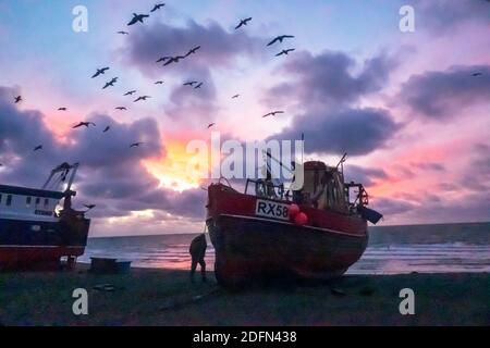 Hastings, East Sussex. Dezember 2020. Möwen wirbeln im Morgengrauen über Hastings Fischerbooten, mit einem bunten Sonnenaufgang über dem Ärmelkanal, am Tag der Gespräche von Boris Johnson mit EU-Kommissionspräsident Ursula von der Leyen, Um zu versuchen, die Sackgasse über die Brexit-Fischereirechte in britischen Gewässern zu brechen und ein Last-Minute-Handelsabkommen zu sichern. VEREINIGTES KÖNIGREICH, EU. Winter Sunrise Großbritannien Stockfoto