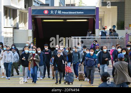 Hongkonger Fußgänger überqueren die Straße, während sie Gesichtsmasken während der Pandemie Covid-19 tragen, Dezember 2020 Stockfoto