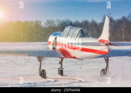 Ein kleines Sportflugzeug rollt auf einem verschneiten Flugplatz. Rückansicht des Flugzeugs Stockfoto