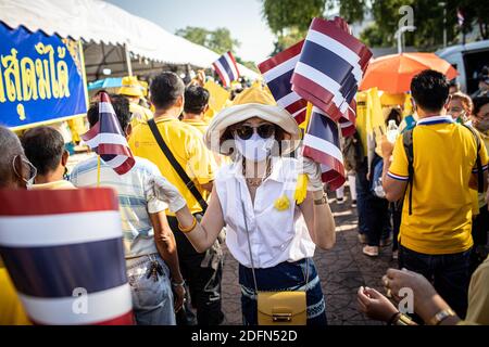 Bangkok, Thailand. Dezember 2020. Ein thailändischer royalistischer Unterstützer verteilt thailändische Nationalflaggen in der Nähe von Sanam Luang während einer Zeremonie zur Feier des Geburtstages des verstorbenen thailändischen Königs Bhumibol Adulyadej (Rama 9). Der thailändische König Maha Vajiralongkorn (Rama 10) nahm zusammen mit anderen Mitgliedern der königlichen Familie an der Zeremonie Teil. Kredit: SOPA Images Limited/Alamy Live Nachrichten Stockfoto