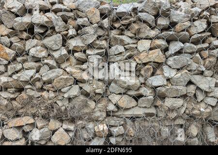 Gabion Zaun aus Netz mit Steinen Stockfoto