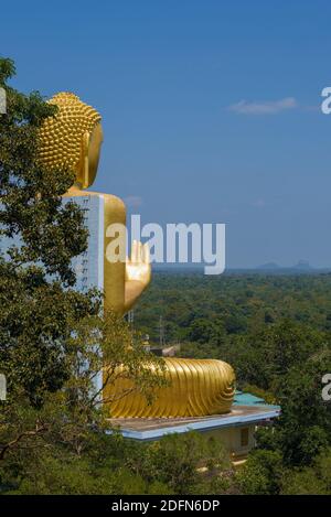 DAMBULLA, SRI LANKA - 08. FEBRUAR 2020: Eine Skulptur eines sitzenden Buddha auf dem Dach des Goldenen Tempels blickt in die Ferne Stockfoto