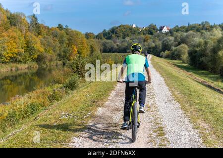 Radler auf Radweg auf dem Kanaldamm der Isar, hinten Grünwalder Burg, Grünwald, Oberbayern, Bayern, Deutschland Stockfoto