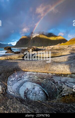 Regenbogen über Bergen am Strand von Utakleiv, Vestvagoya, Lofoten, Norwegen Stockfoto