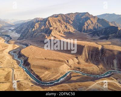 Luftaufnahme von Drohne der Kurve Bergfluss, Fall kahlen Wald, und leere Straße. Schöne Herbst Natur Landschaft Vögel aus der Vogelperspektive. Stockfoto