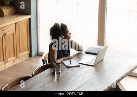 Nachdenkliche afrikanische Ethnizität multirassische Frau in Kopfhörer Blick in der Ferne. Stockfoto