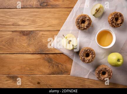 Gebackene Apfelmost-Donuts mit Apfelmost und Früchten auf Backblechen auf natürlichem Holztisch. Bereit, Snack zu essen. Kleine Partie hausgemachtes Essen. Direc Stockfoto