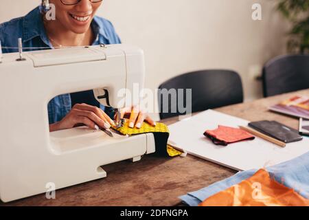 Frau Hände nähen eine Gesichtsmaske zu Hause. Frau, die die Nähmaschine benutzt, um die Gesichtsmasken zu Hause zu nähen. Stockfoto