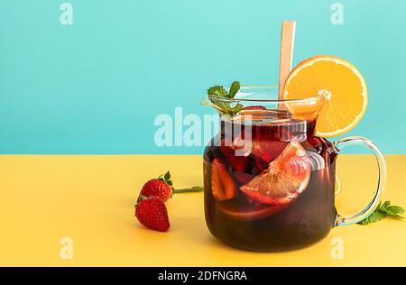 Sommer kalt Cocktail, Obst und Beeren Rotwein Sangria mit Apfel, Zitrone, Orangen und Erdbeere. Blau und gelb Hintergrund, Copy Space. Stockfoto