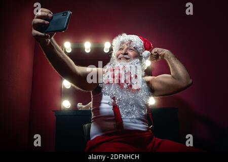 Narzisstischer Weihnachtsmann macht Selfie mit Handy-Kamera In einem Ankleidezimmer Stockfoto