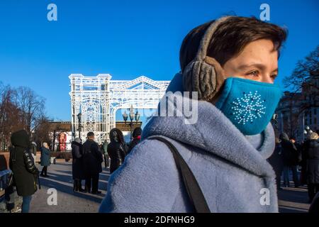 Moskau, Russland. 5. Dezember 2020 Menschen tragen Schutzmasken während eines scharfen kalten Schnapps in der Stadt Moskau vor dem Hintergrund der Installationen des neuen Jahres auf dem Puschkin-Platz im Stadtzentrum, Russland Stockfoto