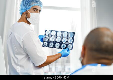 Zwei männliche Ärzte untersuchen MRT-Hirnscans eines Patienten Im Schrank Stockfoto