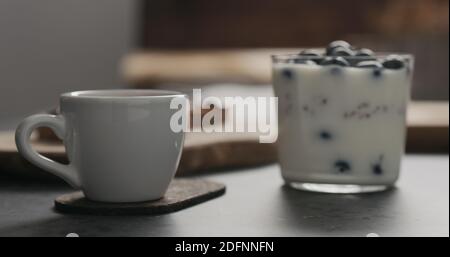 Espresso-Tasse neben Müsli mit Heidelbeeren im Glas mit Kopierraum, breites Foto Stockfoto