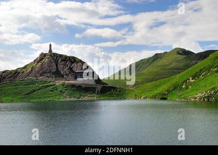 Karnischen Apls, Volaia Pass. Während des Ersten Weltkrieges war es der Schauplatz blutiger Schlachten von italienischen und österreichisch-ungarischen Armeen. Volaia See. Auf dem See war die Front. Im Hintergrund das Denkmal zur Erinnerung an die gefallenen österreichischen Soldaten und die Wolayerseehutte, die Hütte des Österreichischen Alpenvereins. Stockfoto