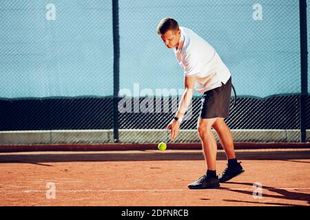 Junger professioneller Tennisspieler, der einen Service leistet Stockfoto