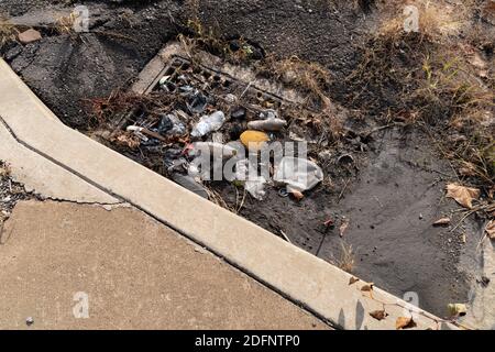 Schlamm und Müll in einem Sturmabfluss neben einem sauberen Bürgersteig, Verschmutzung, horizontaler Aspekt Stockfoto