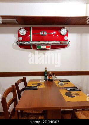 Italienisches Restaurant mit traditionellem Interieur und vorderem Teil Von einem kleinen italienischen Auto als Dekoration Stockfoto