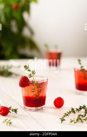 Himbeer-alkoholische Schüsse, Schnapsgläser mit farbigem Schnaps auf weißem Hintergrund Stockfoto