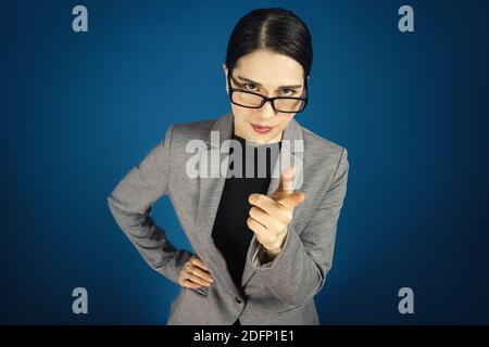 Serious junge schöne Frau in einer grauen Jacke schaut über Brille. Traurige Chefin. Stockfoto