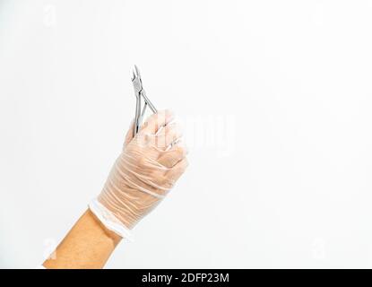 Nahaufnahme der Hand eines mit Handschuhen bemobten Podologen, der eine Schere hält Weißer Hintergrund Stockfoto