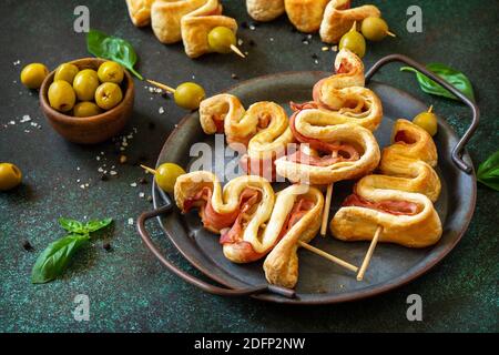 Holiday Snack Blätterteig Weihnachtsbaum mit Oliven und Speck auf einer Schiefer- oder Steinplatte. Weihnachten und Neujahr Hintergrund für Lebensmittel. Stockfoto