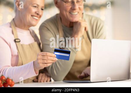 Ältere Paar Mit Kreditkarte Und Laptop Kauf Lebensmittel Im Innen Stockfoto