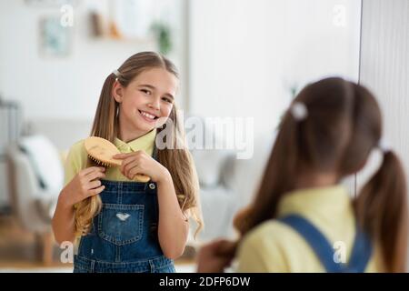 Mädchen vor einem Spiegel, der sich die Haare putzt Stockfoto