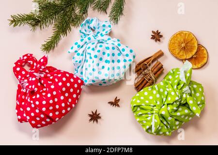 Weihnachtsgeschenke furoshiki auf rosa Hintergrund. Öko weihnachtsfeiertagskonzept. Flache Lay-Ansicht von oben. Stockfoto