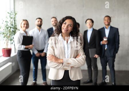 Geschäftsfrau, Die Vor Ihren Angestellten Steht Und Im Büro Posiert Stockfoto