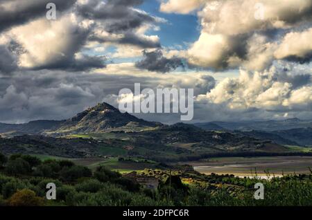 Dramatische Landschaft der Landschaft Siziliens, der Berg von Agira Stadt zeichnet sich zwischen dem stürmischen Wetter auf hügeligem Gelände des sizilianischen Landesinneren Stockfoto