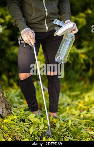 Männliche Freiwillige Abholung Plastikmüll aus Gras Stockfoto