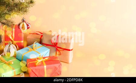 Fabelhafte Geschenke in schönen Schachteln mit Goldbändern unter einem Weihnachtsbaum mit Glasspielzeug verziert. Urlaub. Neujahr und Weihnachten. Postkarte. Kopieren Stockfoto