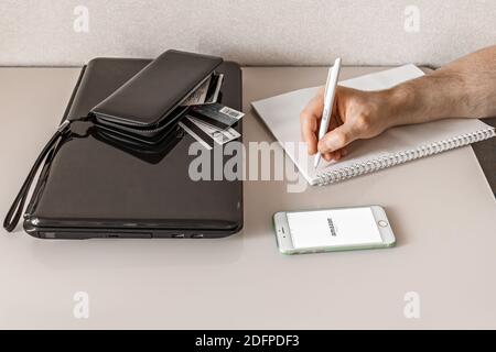 Ein Mann in Quarantäne bestellt Einkäufe online mit Lieferung in einem Online-Shop von zu Hause aus mit einem Smartphone. Prävention von Infektionen während der covid-19 Stockfoto