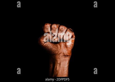 Männliche schwarze Faust auf schwarzem Hintergrund. Aggressivität, Männlichkeit, das Konzept der Herausforderung. Stockfoto