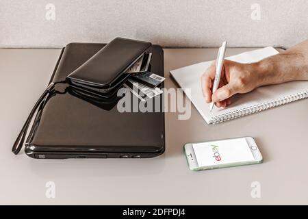 Ein Mann in Quarantäne bestellt Einkäufe online mit Lieferung in einem Online-Shop von zu Hause aus mit einem Smartphone. Prävention von Infektionen während der covid-19 Stockfoto