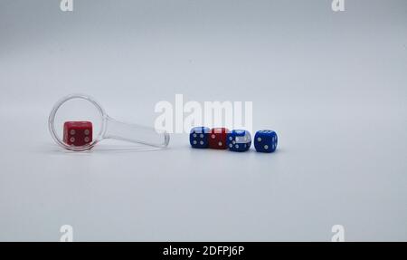Die Lupe schaut auf einen roten Würfel. Das Konzept des Glücksspiels, Spielsucht. Stockfoto