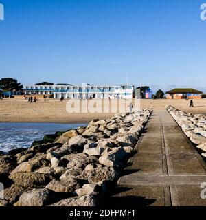 Poole Dorset UK, Dezember 06 2020, Strandhütten am Meer mit Menschen, die zu Fuß klaren blauen Himmel Stockfoto