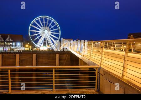 Danzig, Polen - 06. Dezember 2020: Beleuchtete Fußgängerbrücke über den Fluss Motlawa, Riesenrad im Hintergrund in der Altstadt von Danzig Stockfoto