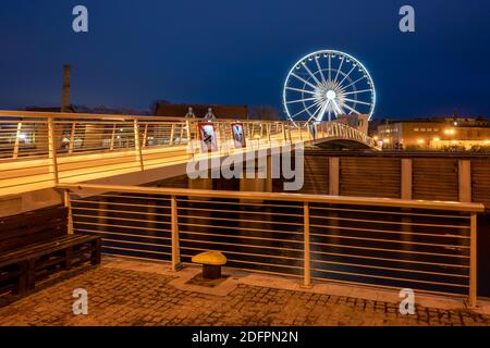 Danzig, Polen - 06. Dezember 2020: Beleuchtete Fußgängerbrücke über den Fluss Motlawa, Riesenrad im Hintergrund in der Altstadt von Danzig Stockfoto
